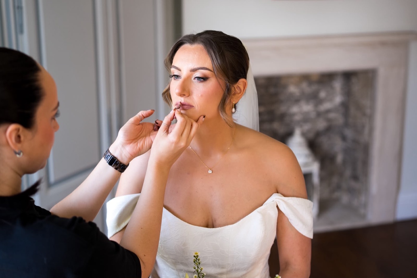 Charly-Ann doing a bride's makeup in a bright room on the wedding morning
