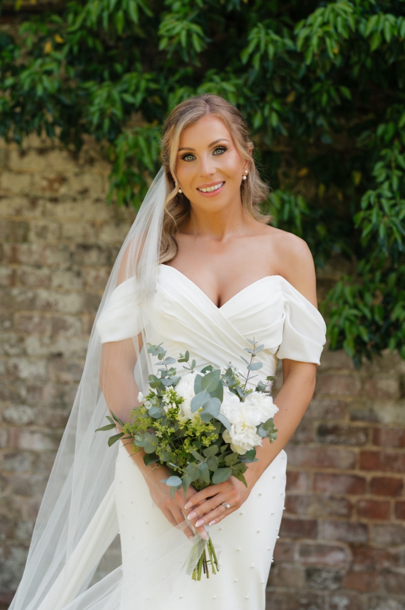 Bride with bouquet in a walled garden